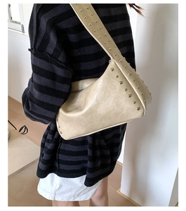 Detail der beigen Nietenschultertasche mit silbernen Metallstiften und Retro PU-Ledertextur
