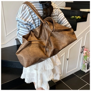 Close-up of a large brown vintage leather tote bag shown in a casual lifestyle setting