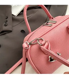 Detailed close-up of pink litchi grain leather texture and silver heart charm
