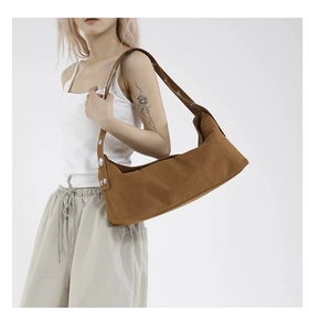 Detail of brown suede shoulder bag featuring decorative silver round metal rivets on the strap