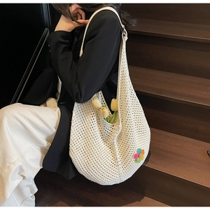 Close-up of beige hollow woven tote bag with colorful flower decor on wooden stairs
