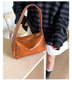 Detail der braunen Vintage-Ledertasche mit Silbernieten und Metallreißverschluss