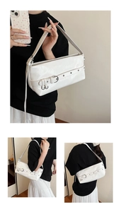 Detail of white baguette bag with pleated leather texture and metallic rivet accents