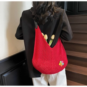 Detail of red hollow knit tote bag with colorful flower patch and black leather handles