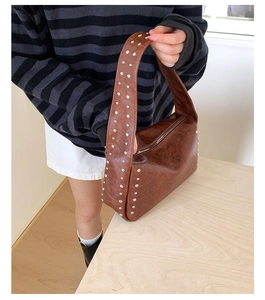 Nahaufnahme der braunen PU-Tasche mit silbernen Nieten und glänzendem Öl-Finish