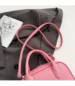 Pink lychee textured mini bowling bag with silver hardware on a grey blazer