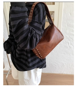 Details der braunen Zylinder-Tasche aus Leder mit Nieten am breiten Schultergurt