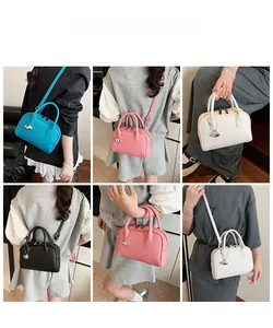 Detailed views of leather boston bag with silver animal charm and adjustable strap