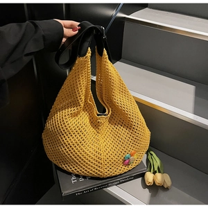 Detailed texture of yellow hand-knitted hobo bag with a 3D floral accent and leather strap