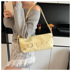 Detail of cream yellow underarm bag with metal eyelets and silver buckle on leather strap