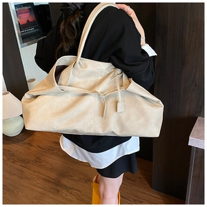 Detail of soft beige vintage tote bag featuring wrinkled texture and strap accent