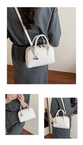 Detailed view of white litchi pattern handbag with silver dolphin pendant and strap
