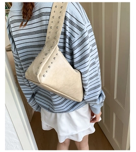Detailansicht der beigen Achseltasche mit Silbernieten am Modell im Freizeit-Look