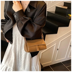 Close-up of brown lychee grain leather crossbody pillow bag with refined strap details