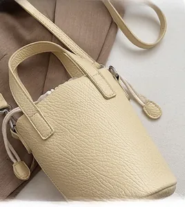 Détail de vue de dessus du sac seau beige avec grain de litchi et fermeture à cordon