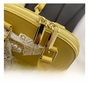 Detailed close-up of yellow pebble leather texture with lace, pearls and gold zippers
