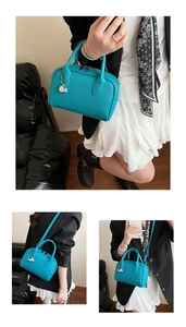 Detailed view of blue litchi grain boston bag with silver dolphin pendant and strap