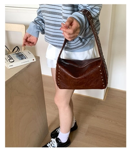 Detailansicht der braunen Lederschultertasche mit Metallnieten und Reißverschluss