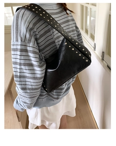 Detail der schwarzen PU-Schultertasche mit runden Metallnieten und minimalistischer Form