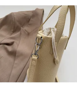Gros plan du sac seau beige avec boucle en métal argenté et texture cuir grainé