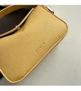 Détail en cuir grainé jaune avec logo CLEAROK embossé et boucle en métal argenté