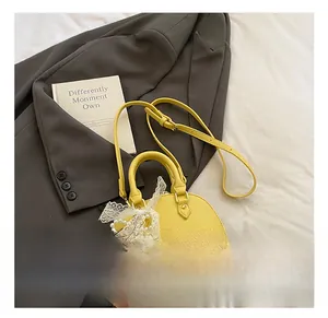 Detail of yellow lychee leather shell bag with white lace bow and pearl charm ornament