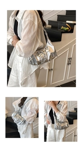 Detail der silbernen Metallic-Unterarmtasche mit gewebtem Design und Faltenstruktur