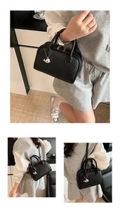 Detail of black litchi grain leather Boston bag with silver whale charm and dual handles
