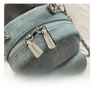 Detailed close-up of premium silver metal zippers on light blue denim mini backpack