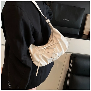 Detailed view of cream moon bag with lace-up ribbon detail and adjustable strap