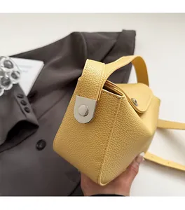 Gros plan d'un sac à main jaune en cuir grainé avec boucle en métal argenté et poignée