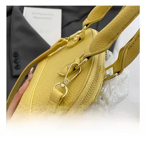 Detailed macro view of yellow lychee grain leather handbag with gold metal hardware