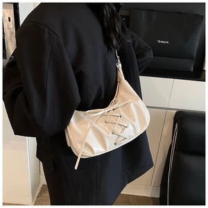 Close-up of cream-white dumpling bag with cross-strap design and glossy leather finish