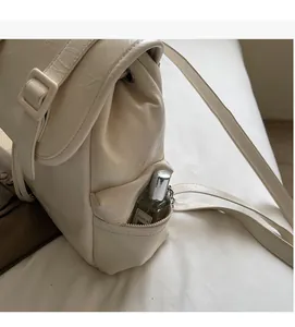 Détail d'une poche zippée sur sac à dos crème en cuir PU avec un petit flacon de parfum