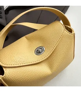 Détail du sac à main jaune en cuir avec texture grainée et fermoir pivotant argenté