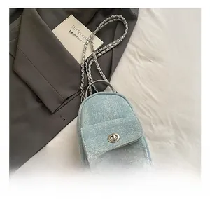 Detail of mini light blue denim backpack with silver metal twist lock and chain strap