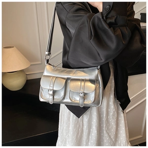 Detail of silver metallic tote bag featuring dual front pockets and glossy PU leather texture
