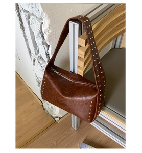 Detail einer braunen Ölwachs-Ledertasche mit silbernen Nieten und Reißverschluss-Detail