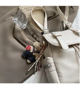 Détail du sac à dos en similicuir crème avec texture froissée et boucles métalliques
