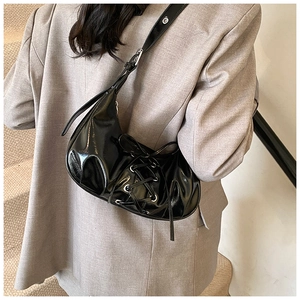 Detail der schwarzen Lackleder-Tasche mit Schnürdesign und silbernen Metallösen