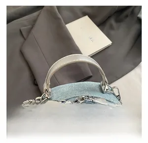 Macro view of light blue denim mini backpack showing silver PU handles and zipper detail