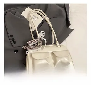 White glossy shoulder bag detail showing double front pockets and lace bow charm