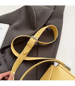 Détail de la bandoulière en cuir jaune grainé avec boucle réglable en argent poli