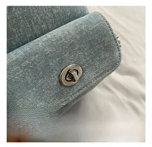 Detailed macro view of the silver metal swivel lock on a blue denim handbag texture