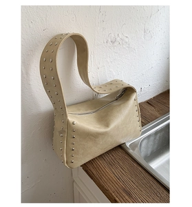 Detail der cremefarbenen Ledertasche mit silbernen Nieten und Faltenstruktur