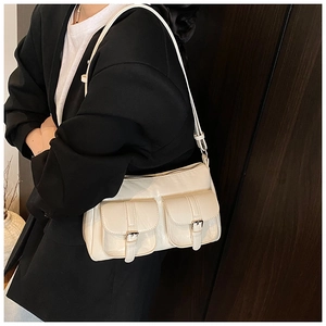 Dettaglio della borsa baguette crema con multitasche indossata con blazer nero