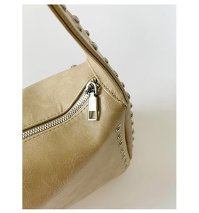 Detailansicht der beigen Ledertasche mit silbernen Nieten und Metallreißverschluss