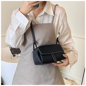 Detail of black pebbled leather crossbody bag with contrasting white stitching