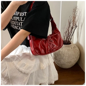 Detail of burgundy patent leather bag with lace-up drawstring and metal eyelets