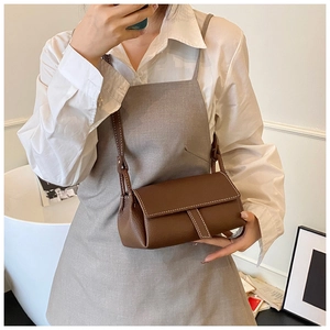 Detailed view of brown litchi grain leather texture and contrast stitching on a crossbody bag